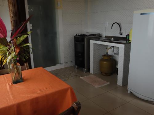 a kitchen with a table and a sink and a refrigerator at Bem Me Quer Casas in Morro de São Paulo