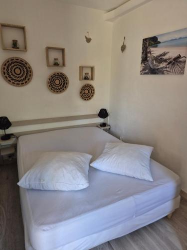 ein weißes Bett in einem Zimmer mit zwei Kissen in der Unterkunft Havre de paix appart climatisé,piscine,wifi in Le Barcarès