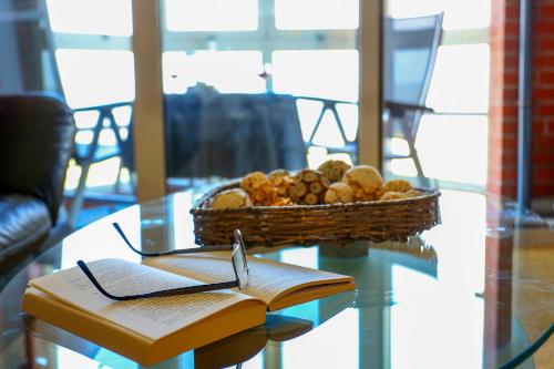 a glass table with a basket of fruit and a book at Haus Horizont I HZ21 in Cuxhaven