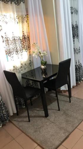 a black table and chairs in a room with curtains at Sacha studio chic etoug ebe in Yaoundé