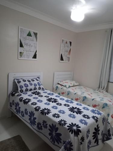 a bedroom with two beds with blue and white sheets at Quarto em apartamento no cabula in Salvador
