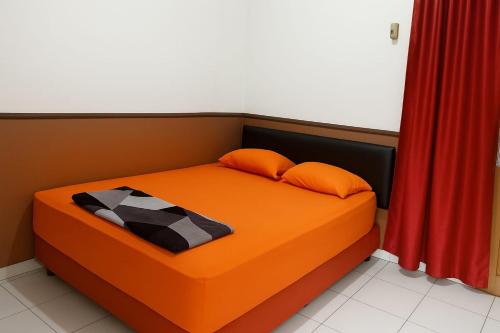 an orange bed in a room with a red curtain at Citytel Kostel in Lampung