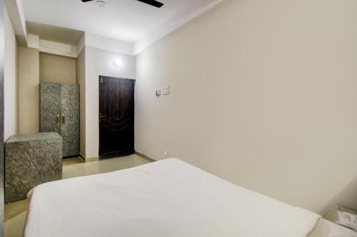 a bedroom with a white bed and a black door at Hotel O Sai villa in Dispur