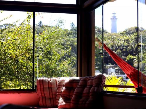 a couch in front of a window with a lighthouse at Bem Me Quer Casas in Morro de São Paulo