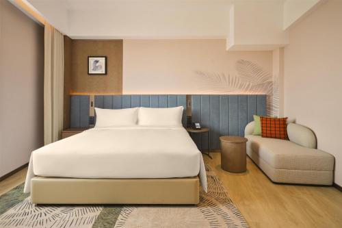 a bedroom with a large bed and a chair at Hilton Garden Inn Yingkou Zhanqian in Yingkou