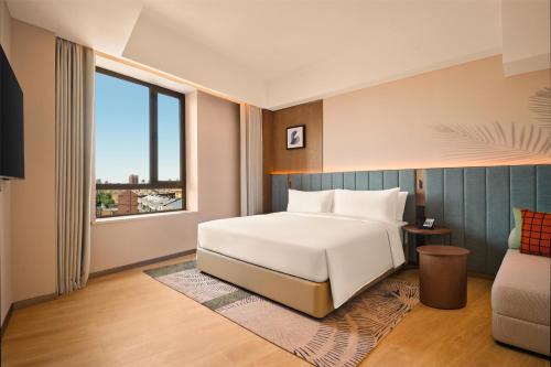 a bedroom with a white bed and a large window at Hilton Garden Inn Yingkou Zhanqian in Yingkou