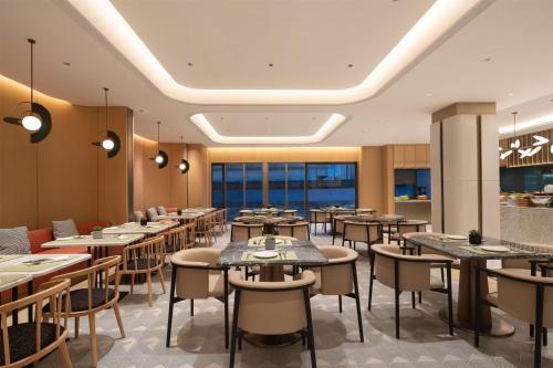 a restaurant with tables and chairs and windows at Hilton Garden Inn Shaoxing Yuecheng in Shaoxing