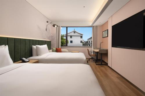 a hotel room with two beds and a flat screen tv at Hilton Garden Inn Shaoxing Yuecheng in Shaoxing