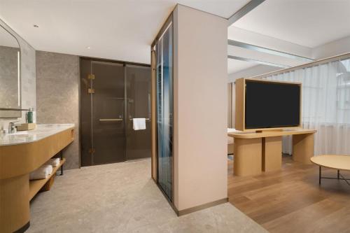 a bathroom with a television and a desk with a sink at Hilton Garden Inn Shaoxing Yuecheng in Shaoxing