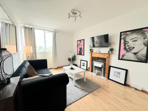 a living room with a black couch and a fireplace at Green Woods Lovely 1 Bed Apt in Blackheath, London in London