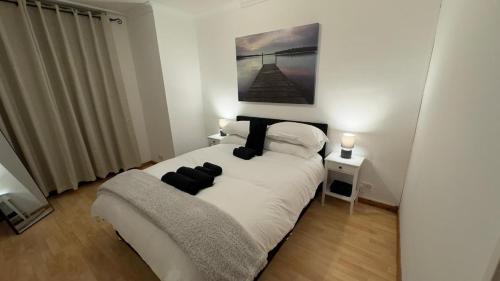 a bedroom with a white bed with black pillows at Green Woods Lovely 1 Bed Apt in Blackheath, London in London