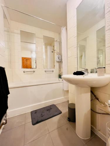 a white bathroom with a sink and a bath tub at Green Woods Lovely 1 Bed Apt in Blackheath, London in London