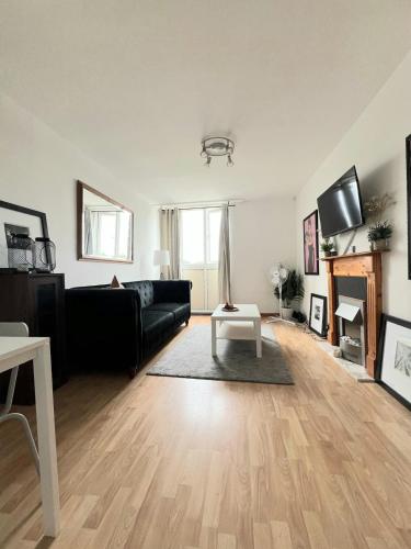 a living room with a black couch and a fireplace at Green Woods Lovely 1 Bed Apt in Blackheath, London in London