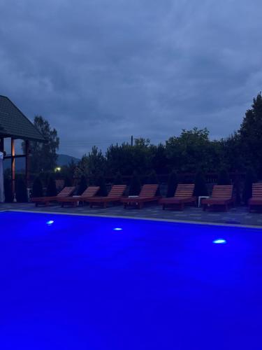 a row of benches sitting next to a pool at night at Готель TWINS РАЙ in Vorokhta