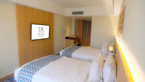 a hotel room with two beds and a tv on the wall at Louis Kienne Hotel Simpang Lima in Semarang