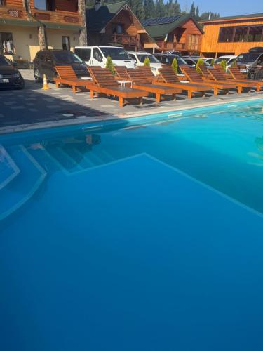 a row of wooden benches next to a swimming pool at Готель TWINS РАЙ in Vorokhta