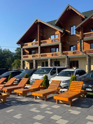 a row of wooden benches in front of a building at Готель TWINS РАЙ in Vorokhta