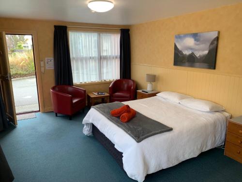 une chambre d'hôtel avec un lit avec un animal en peluche rouge dessus dans l'établissement Red Tussock Motel, à Te Anau