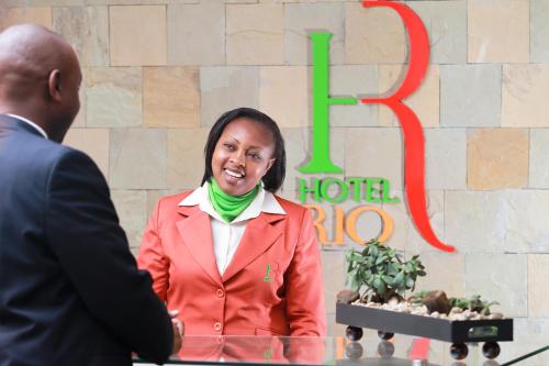 a woman in a red suit talking to a man at Hotel Rio in Nairobi
