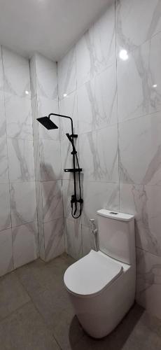 a white bathroom with a toilet in a room at Emerald Villa in Prampuan