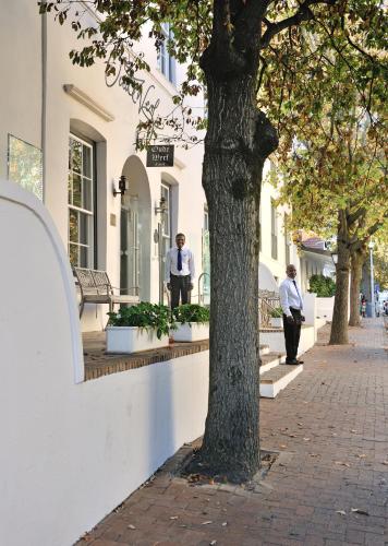 two men standing outside of a building next to a tree at Oude Werf Hotel in Stellenbosch