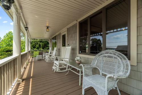 a porch with white wicker chairs and a table at Grammy's Famous Lake House Retreat in East Hampton