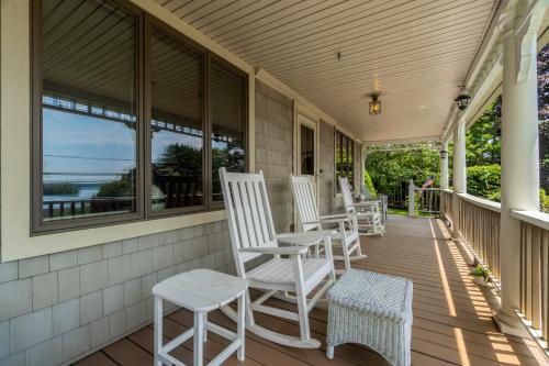 a porch with white rocking chairs and windows at Grammy's Famous Lake House Retreat in East Hampton