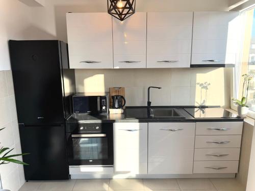 a kitchen with a black refrigerator and white cabinets at Lux apartment in Belgrade