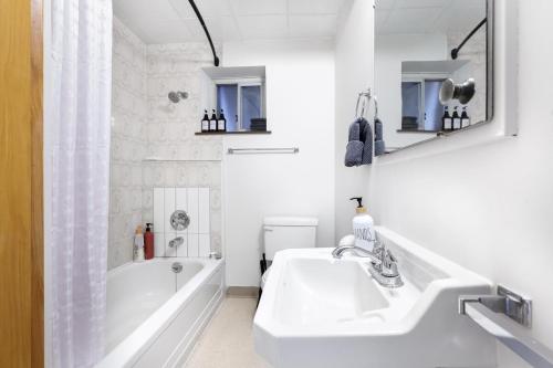 un bagno bianco con vasca e lavandino di Cozy Basement 1 BR Suite King & Queen Beds, Sleeps 6, Street Parking a Burnaby