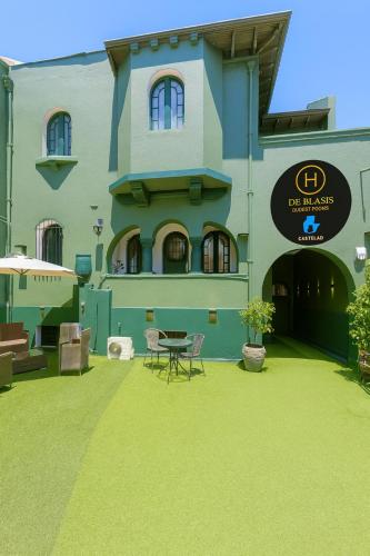 a building with a green yard with a table and chairs at De Blasis Budget Rooms in Santiago