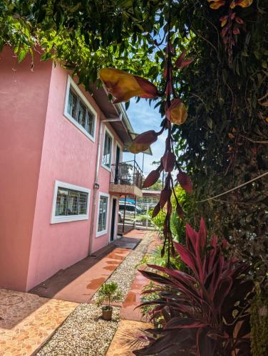 a house with pink walls and a walkway at Departamento Ángeles del Arenal #1 in Fortuna