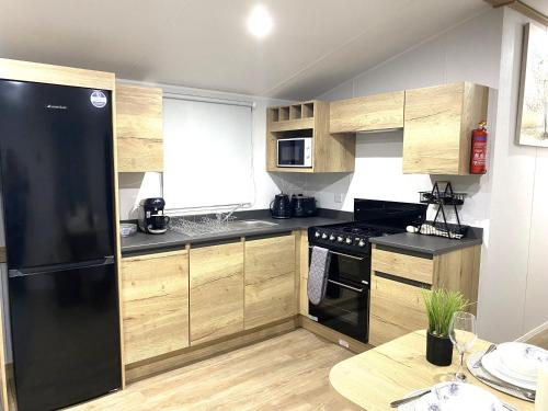 a kitchen with a black refrigerator and wooden cabinets at BAF Luxury Stays - Billing Aquadrome - Caravan Sleeps 8 in Great Billing