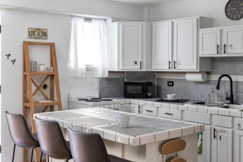 a kitchen with white cabinets and a table with chairs at Waikiki Escape King Bed Pool Walk to Beach in Honolulu
