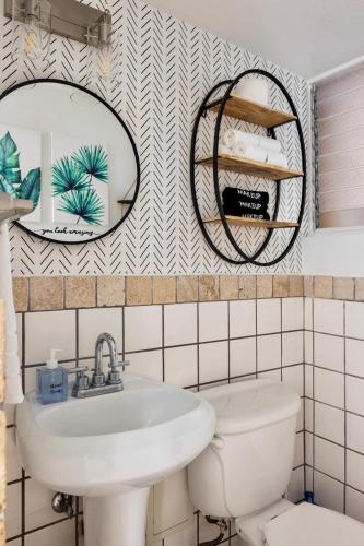a bathroom with a sink and a mirror and a toilet at Waikiki Escape King Bed Pool Walk to Beach in Honolulu