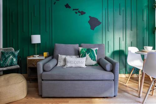 a living room with a couch and a green wall at Waikiki Escape King Bed Pool Walk to Beach in Honolulu