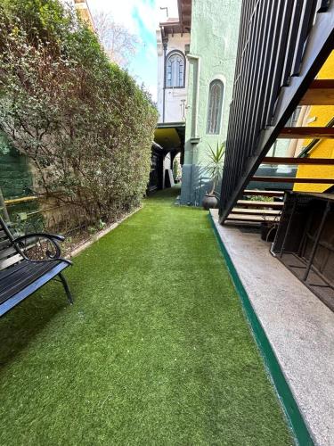 a bench sitting on the grass next to a building at De Blasis Budget Rooms in Santiago