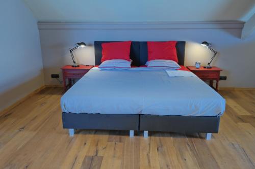- un lit avec 2 oreillers rouges dans l'établissement Den Dilte, à Jabbeke