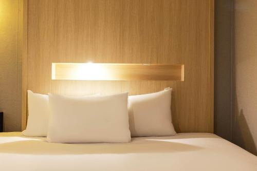 a bed with white pillows and a wooden headboard at Signature Tourist Hotel in Seoul