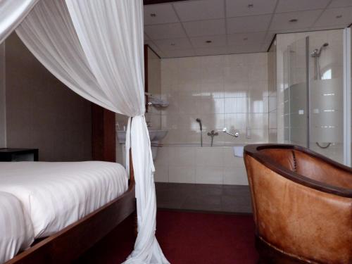 a bedroom with a bed and a shower and a tub at Hotel Wienerhof in Den Helder