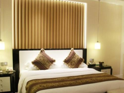 a bedroom with a large white bed with two pillows at Tongxiang Inspirock Hotel in Jiaxing