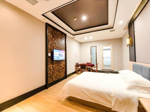 a bedroom with a bed and a tv on the wall at 7Days Premium Yichang Railway Station East in Yichang