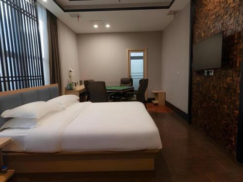 a bedroom with a bed and a table and a tv at 7Days Premium Yichang Railway Station East in Yichang