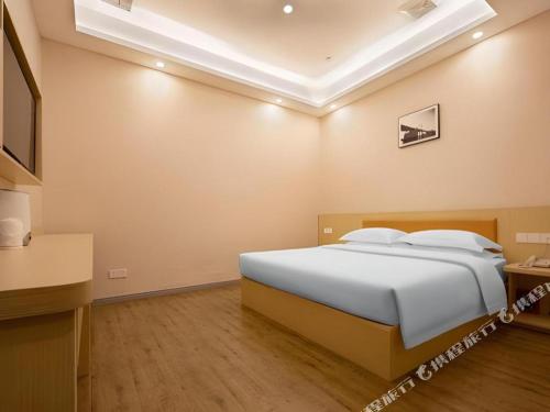 a bedroom with a large white bed in a room at 7Days Premium Yichang Railway Station East in Yichang