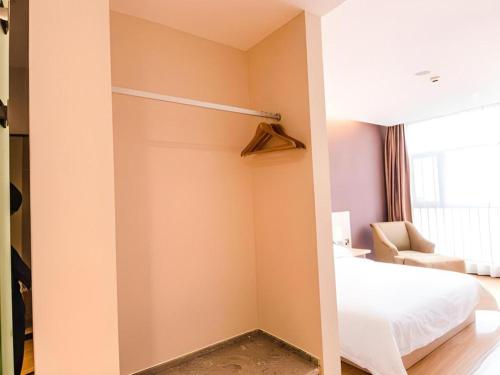 a bedroom with a closet with a bed and a couch at 7Days Premium Yichang Railway Station East in Yichang