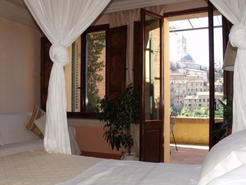 a bedroom with a bed and a view of a city at Residenza d'Epoca Campo Regio Relais in Siena