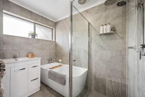 a bathroom with a shower and a tub and a sink at Ultima Escapes - Carcoola House - Barossa Fringe Retreat in Greenock