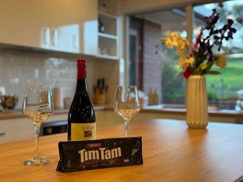 a bottle of wine and two wine glasses on a table at Ultima Escapes - Carcoola House - Barossa Fringe Retreat in Greenock