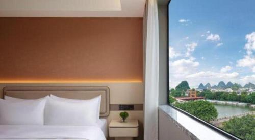 a bedroom with a bed and a window with a view at Immersing Hotel Guilin Two Rivers and Four Lakes Dongxi Alley in Guilin
