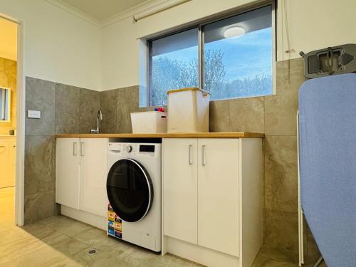 a washing machine in a kitchen with a window at Ultima Escapes - Carcoola House - Barossa Fringe Retreat in Greenock