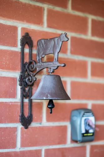 a bell with a cow on it hanging on a brick wall at Ultima Escapes - Carcoola House - Barossa Fringe Retreat in Greenock